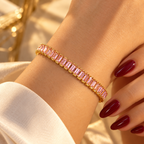 Gold-tone stainless steel tennis bracelet set with pink zircon stones.