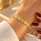 Gold stainless steel bracelet featuring a faceted cube design and screw engravings.