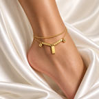 Double-strand stainless steel anklet with cube links and a gold charm.
