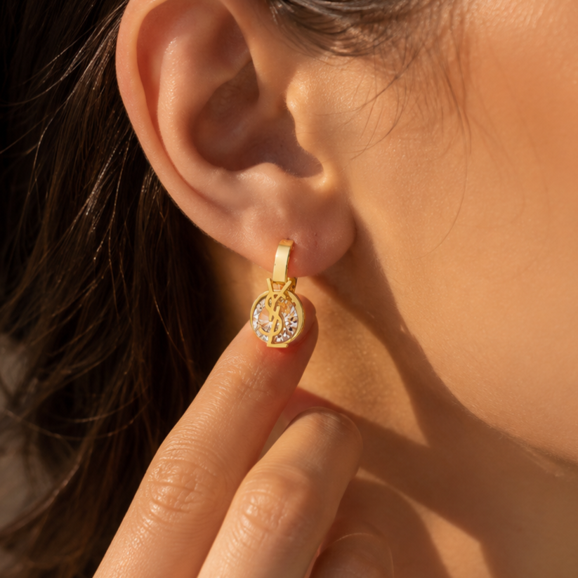 Gold-plated stainless steel earrings with an interlocking letter design and crystal stone