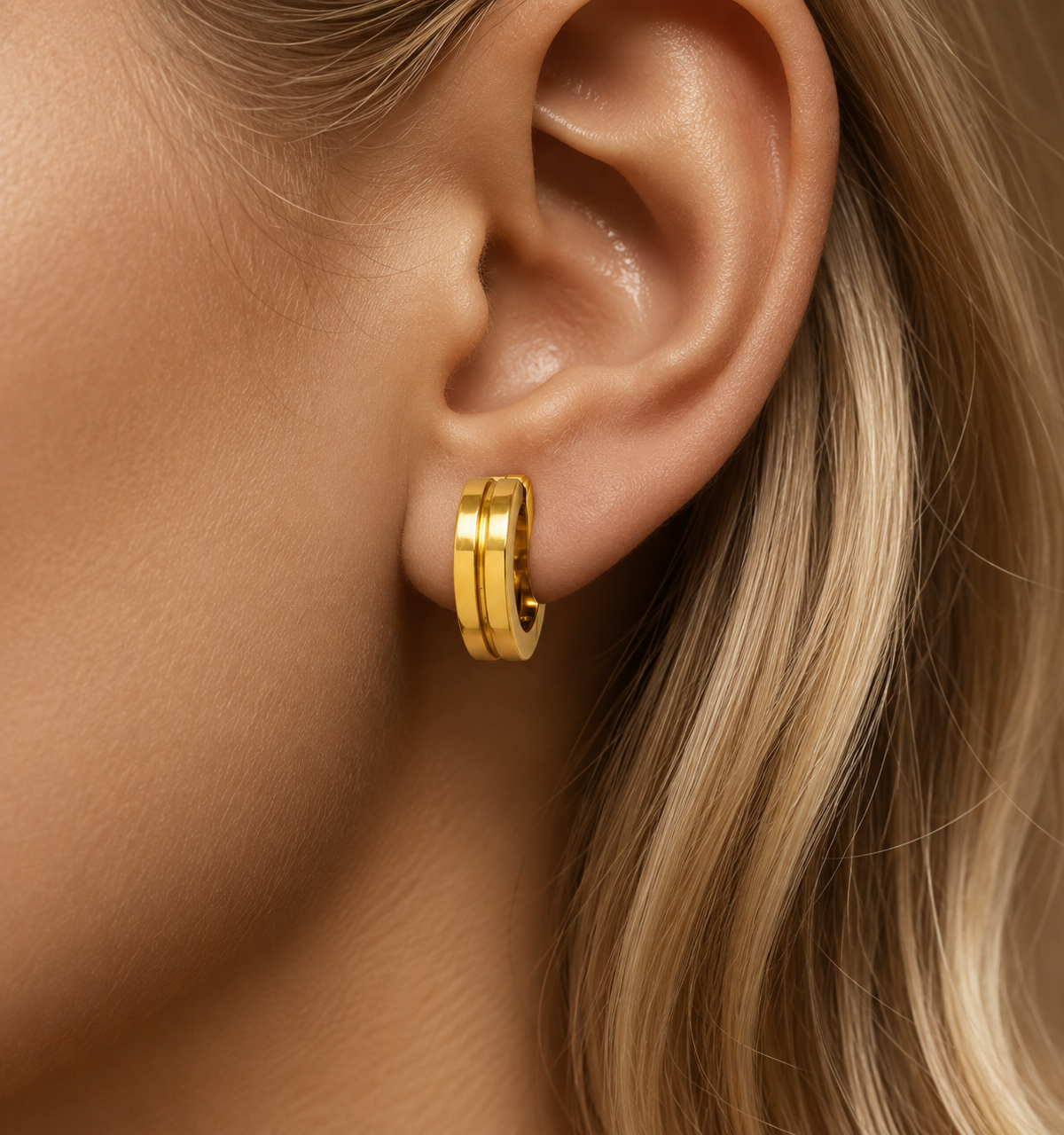 Small stainless steel hoop earrings with gold engraved lines.