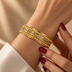 Stainless steel bracelet with Greek-style engraving and gold beads.