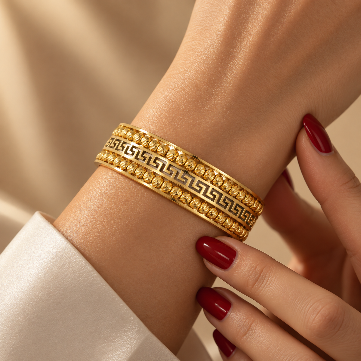 Stainless steel bracelet with Greek-style engraving and gold beads.
