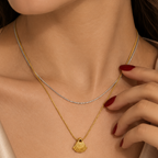 Double-strand stainless steel necklace with a gold seashell pendant.